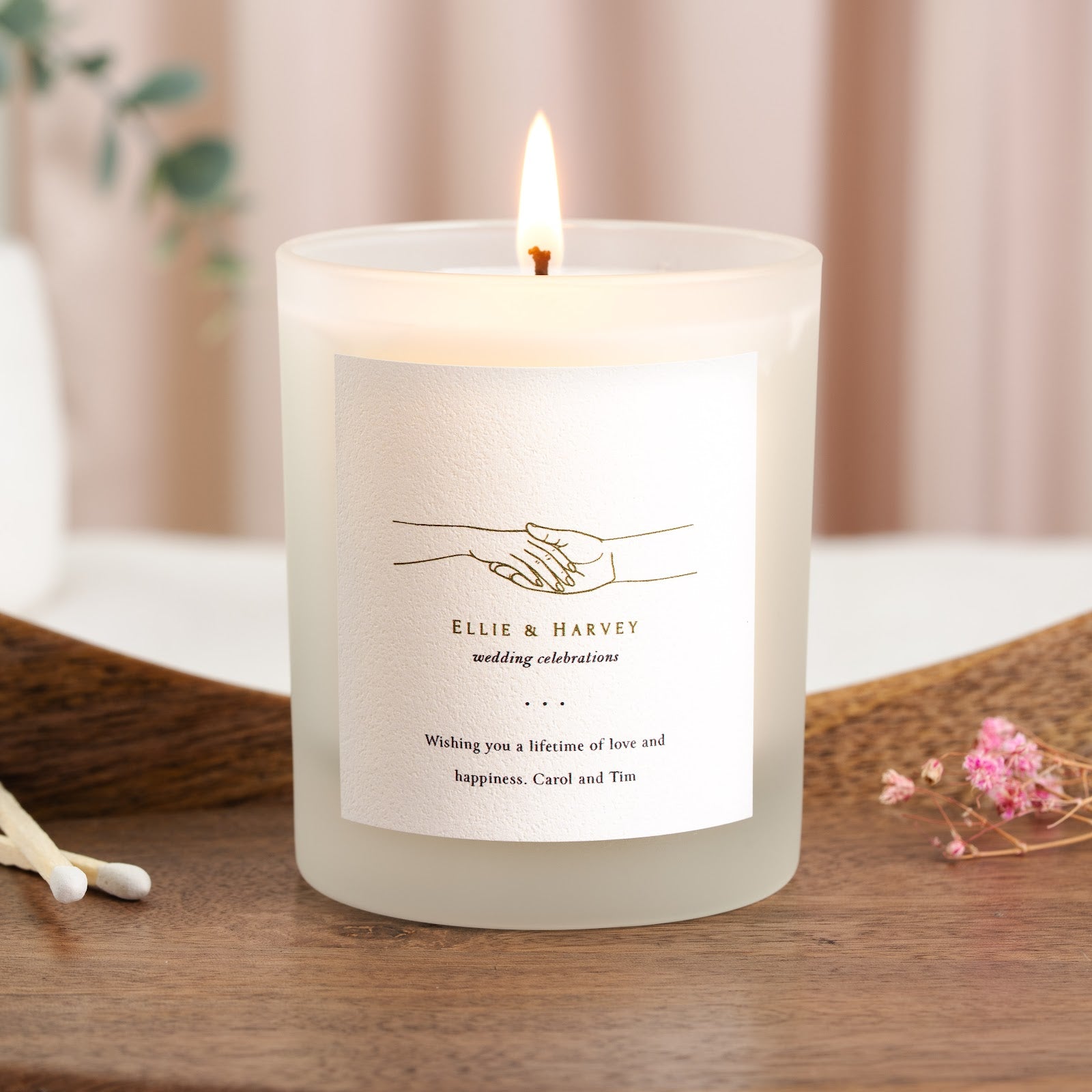 Fine gold line drawing of two clasped hands on a personalised wedding candle label