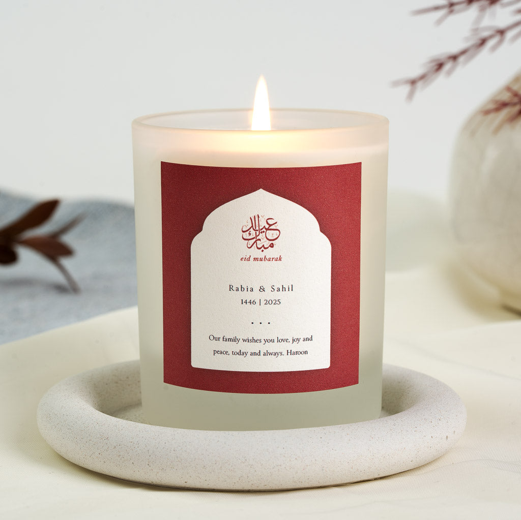 Gold-toned Arabic calligraphy inside a white arch on a crimson personalised Eid candle