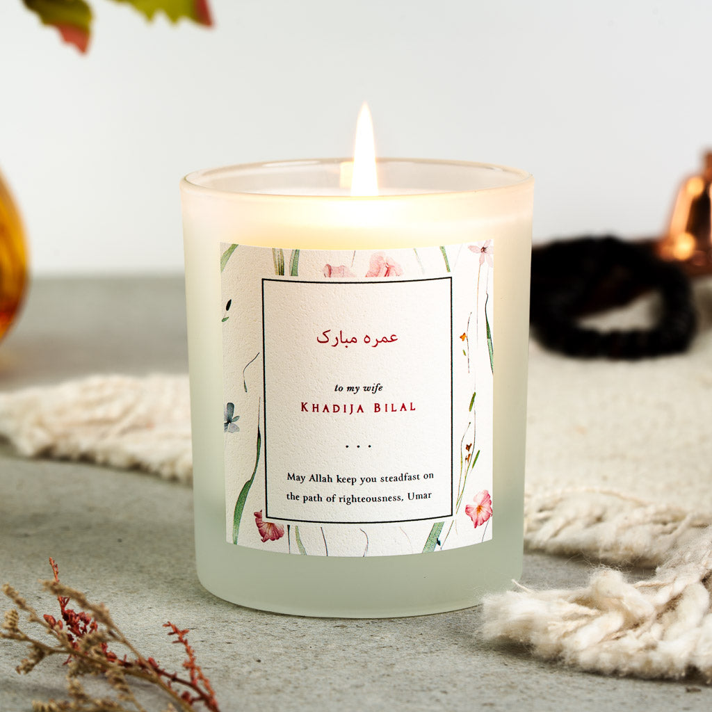Floral border framing a bordered Arabic panel on a personalised Umrah candle label