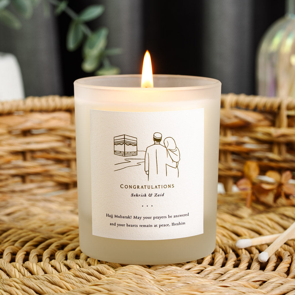 Gold line art of a couple walking towards the Kaaba on a personalised Hajj candle label