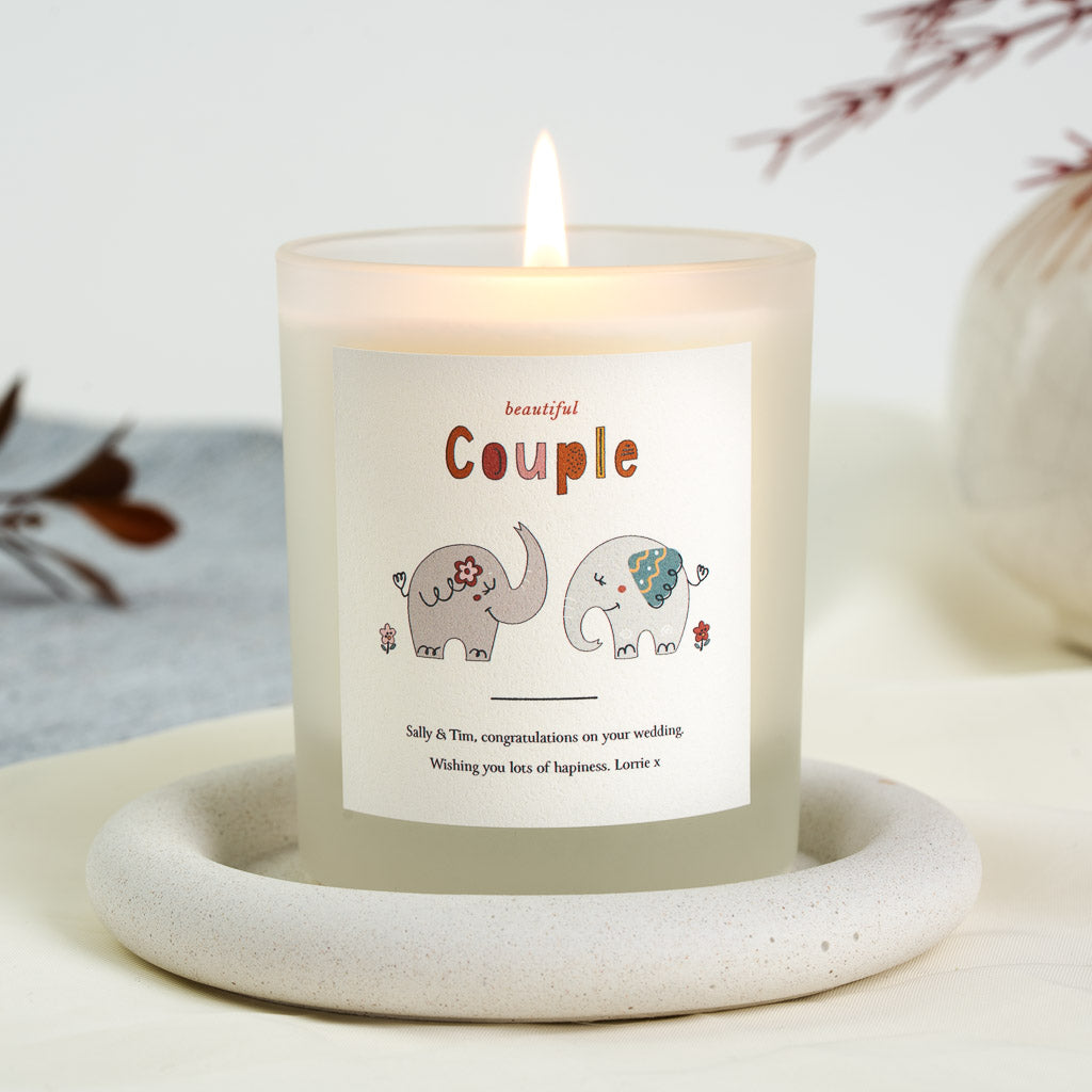 Personalised wedding candle with two hand-drawn elephants facing each other beneath warm orange lettering