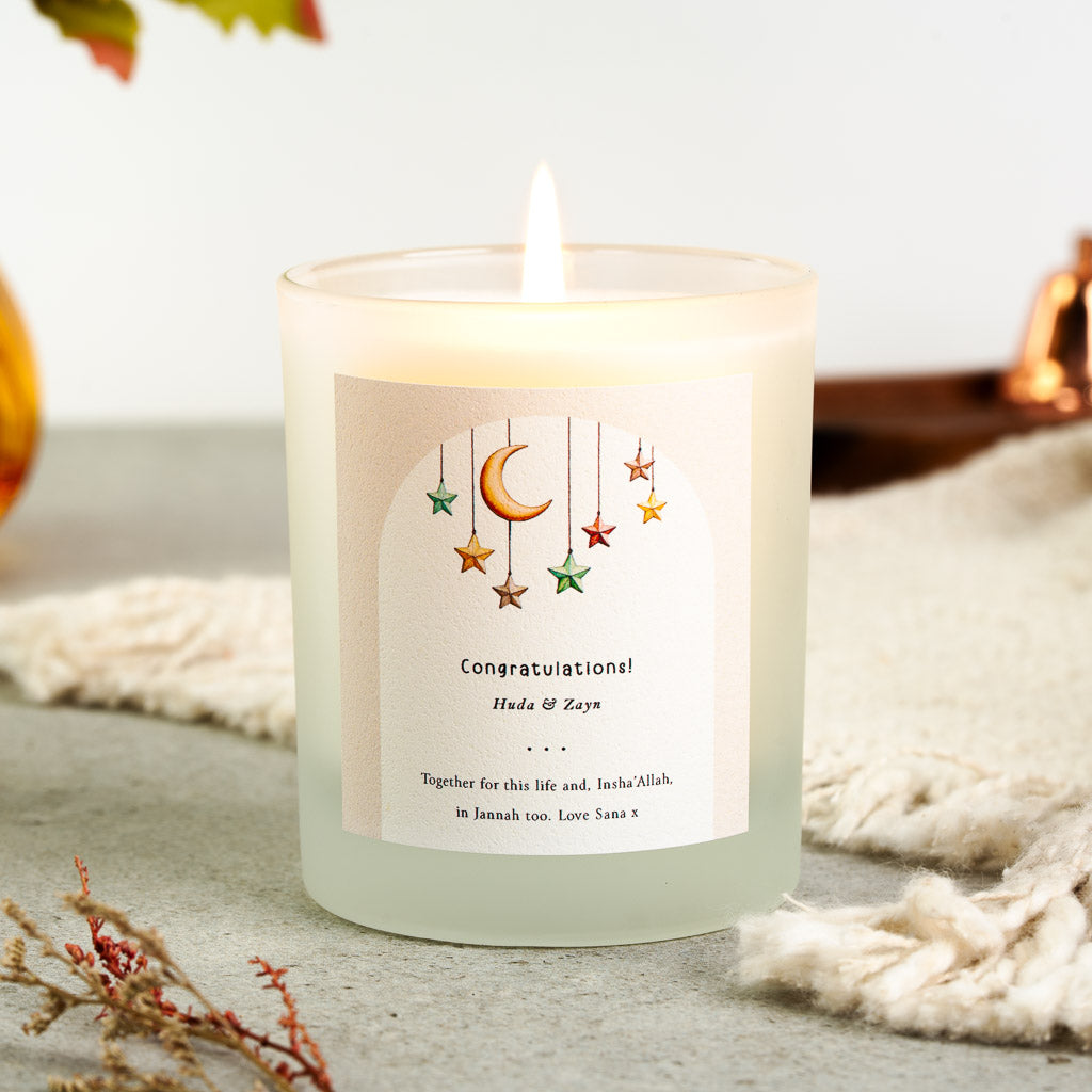 Hanging stars and a gold crescent moon on a blush arch on a personalised engagement candle