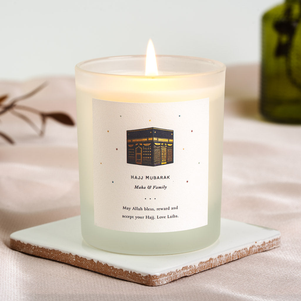 Personalised Hajj candle with a stylised Kaaba in warm gold and deep navy at the centre