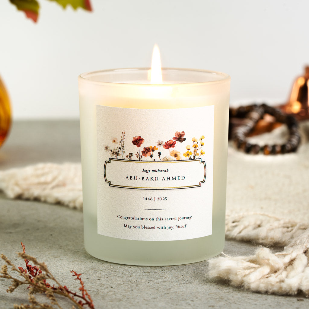 Wildflowers framing a boxed hajj mubarak panel on a personalised Hajj candle label