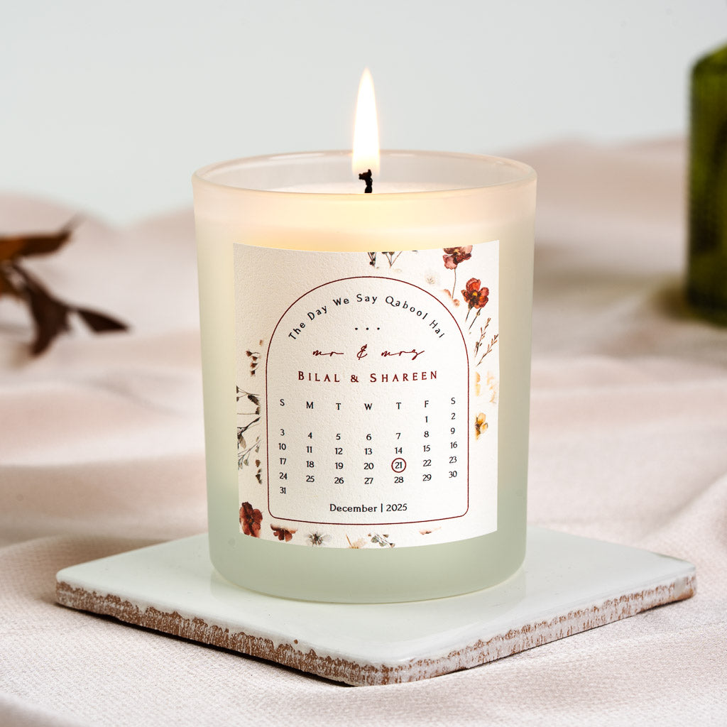 Personalised nikah candle with pressed wildflowers framing an arched calendar and circled date