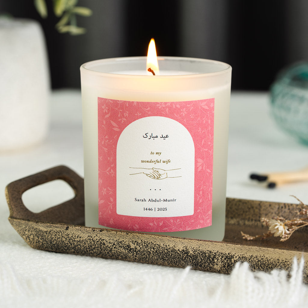 Personalised Eid candle with a clasped-hands illustration inside a white arch