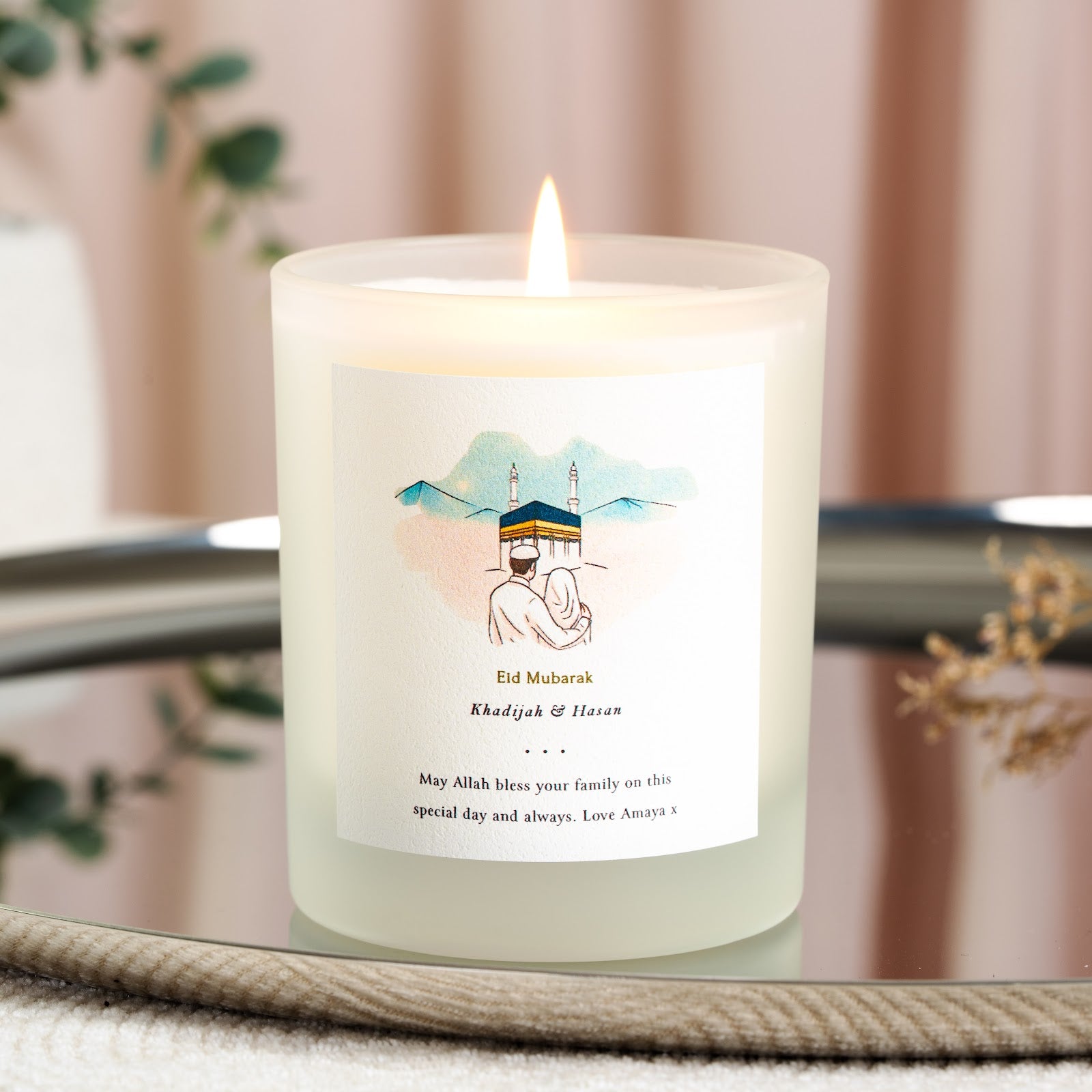 Watercolour couple facing the Kaaba in soft blue and peach on a personalised Eid candle