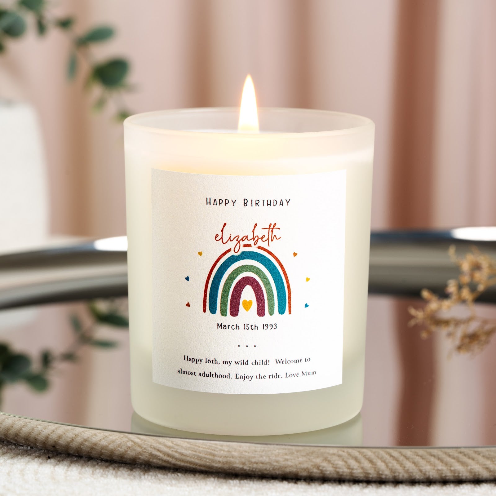 Bright rainbow illustration beneath red script lettering on a personalised birthday candle