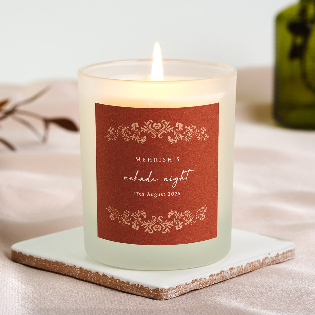 Personalised mehndi candle with a decorative floral border on a solid rust-red label