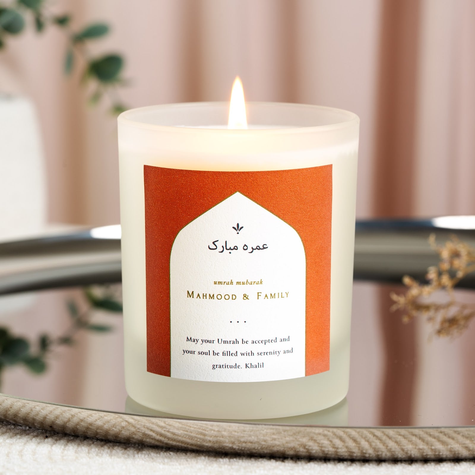 Arch-shaped label on a terracotta background on a personalised Umrah candle