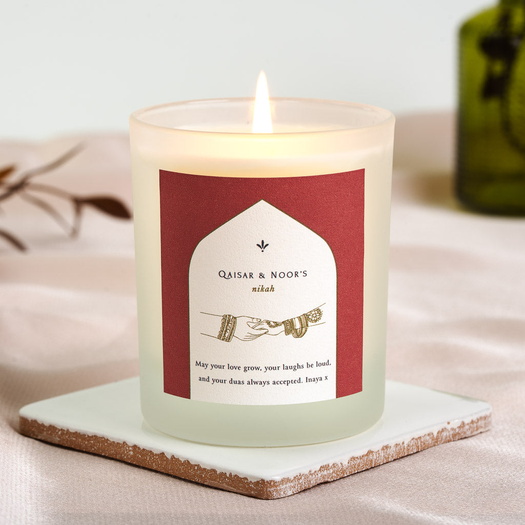 Personalised nikah candle with a small leaf motif above a white arch on deep red