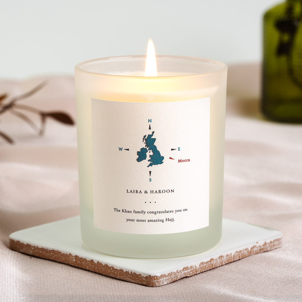 Personalised Hajj candle with a compass and teal UK map marking Mecca above the couple's names