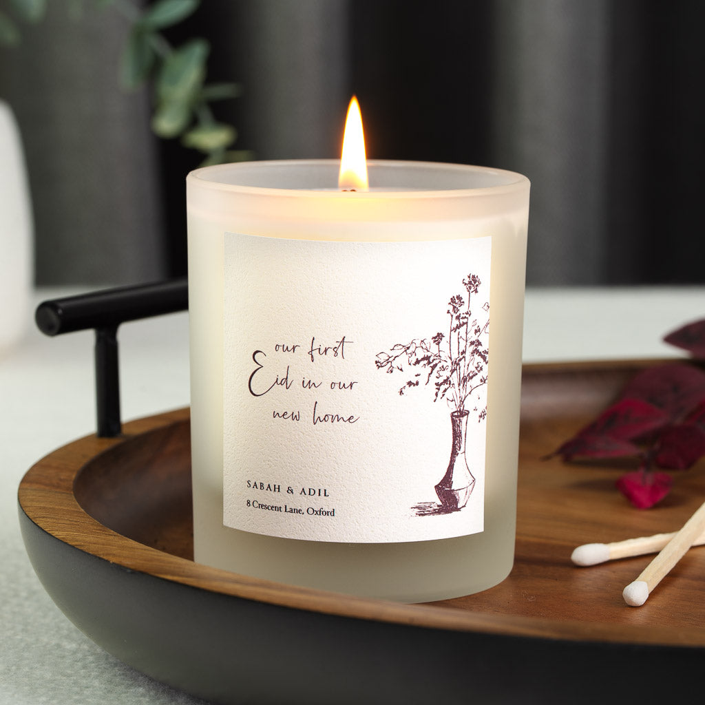 Sketched vase of branches in deep red ink beside cursive text on a personalised home candle
