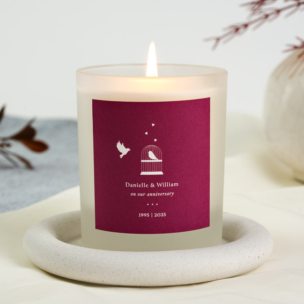 Personalised anniversary candle with a white dove and birdcage on a berry red panel
