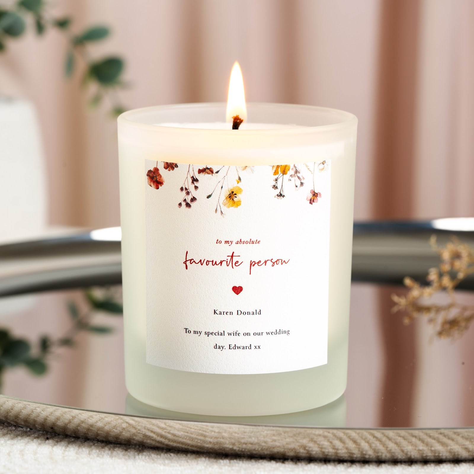 Warm watercolour flowers above red script and a small heart on a personalised wedding candle