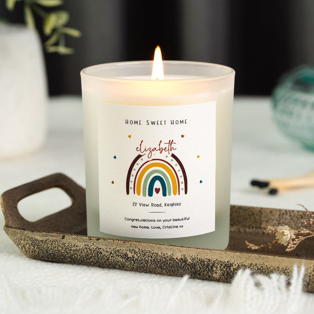 Personalised housewarming candle with a rainbow beneath an arched script name