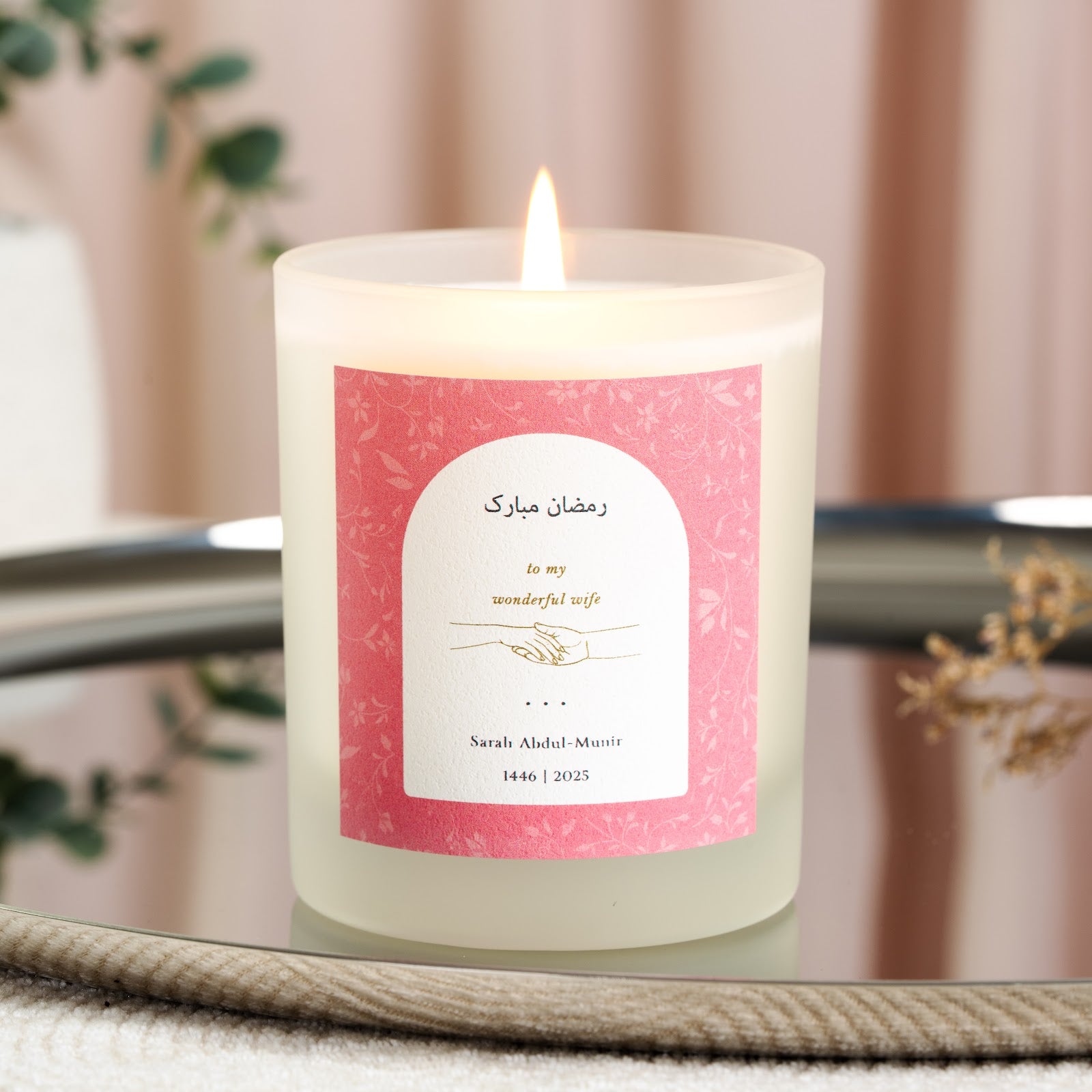 Fine floral linework on a dusky pink backdrop behind an arch on a personalised Ramadan candle