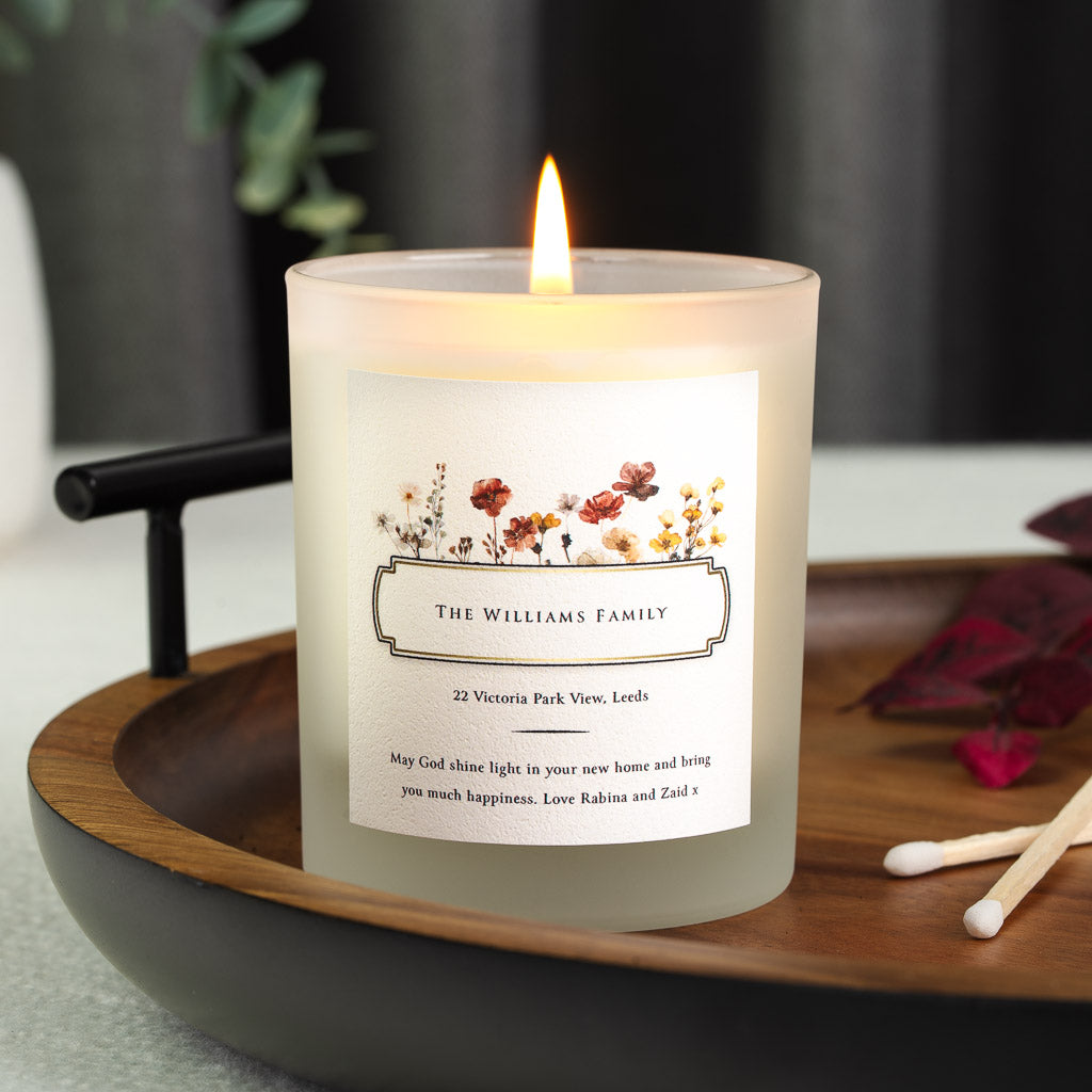 Pressed-style wildflowers above a framed nameplate on a personalised new home candle