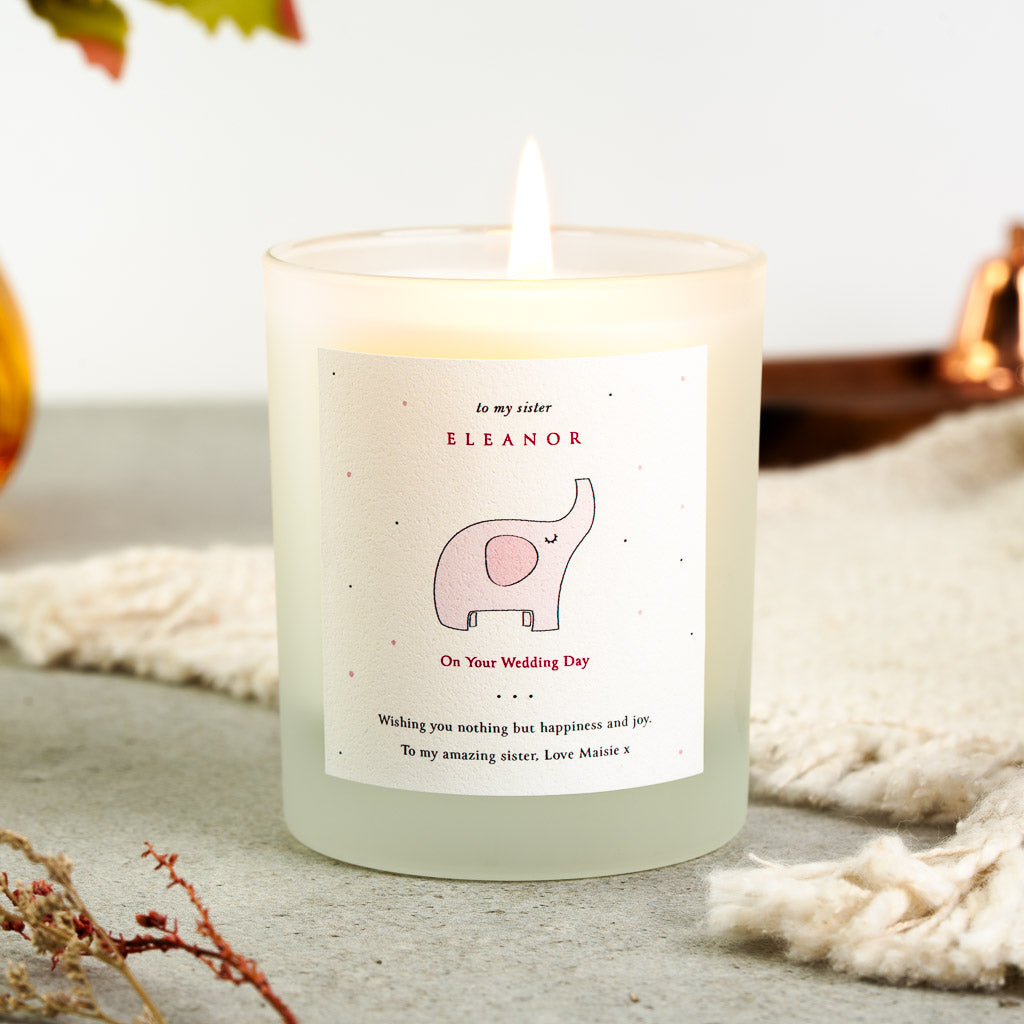 Pink elephant illustration above red capital lettering on a personalised wedding candle