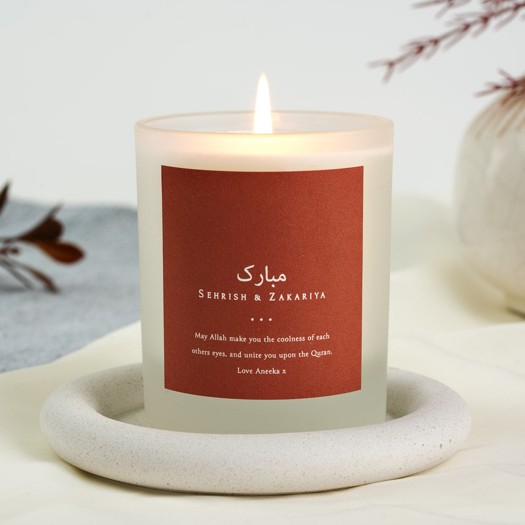 White script on a solid rust-red background on a personalised nikah mubarak candle label