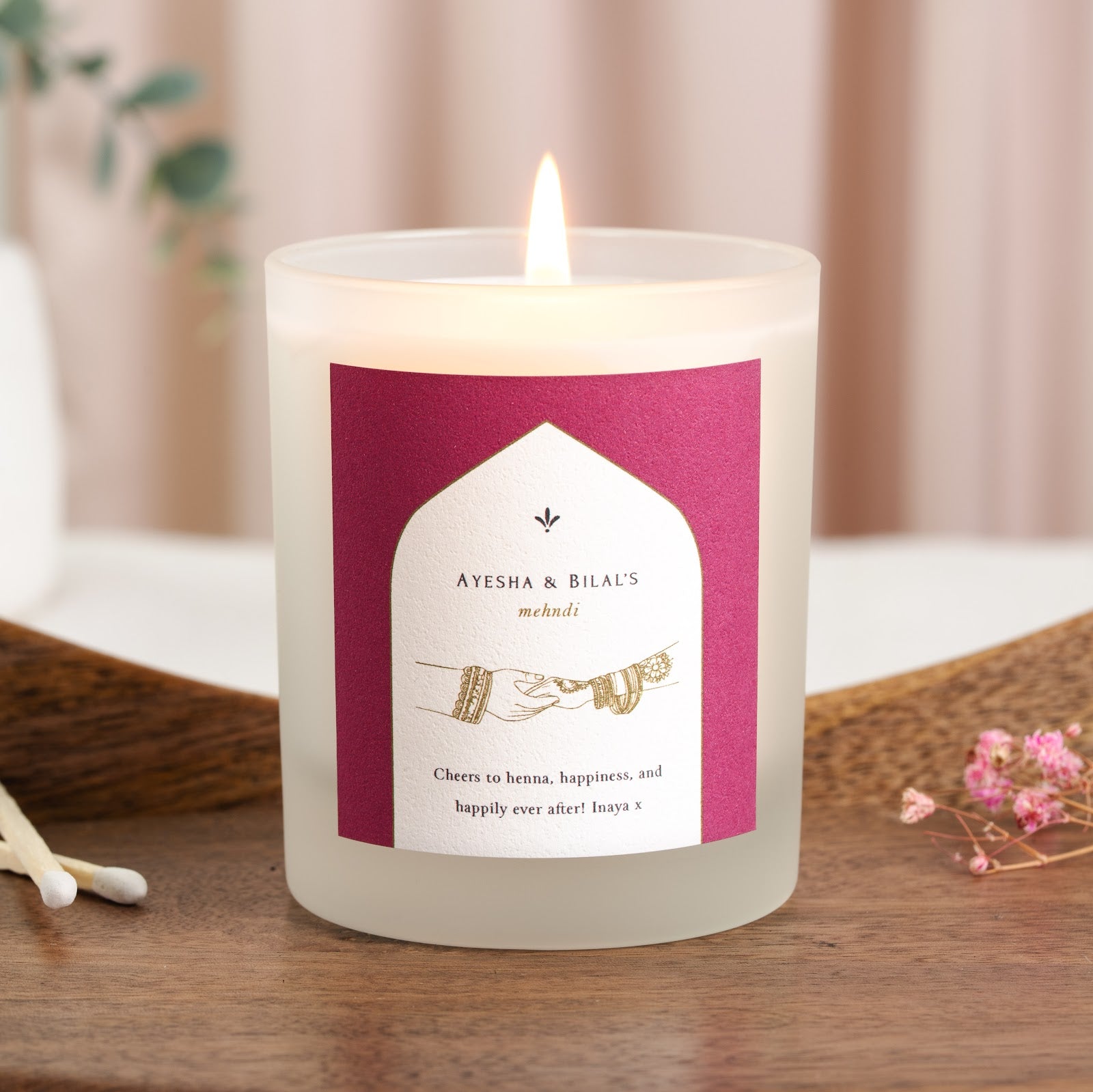 White arch on magenta holding a line drawing of hennaed hands on a personalised mehndi candle