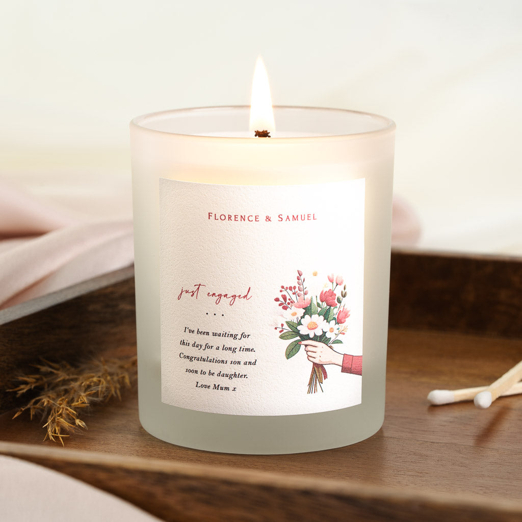 Personalised engagement candle with just engaged script set beside a bouquet illustration