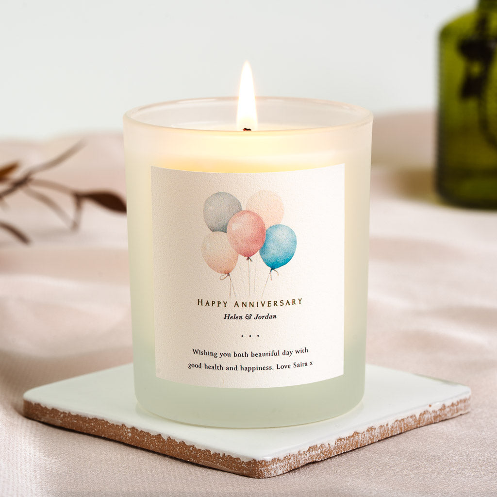 Personalised anniversary candle with pastel balloons above happy anniversary lettering