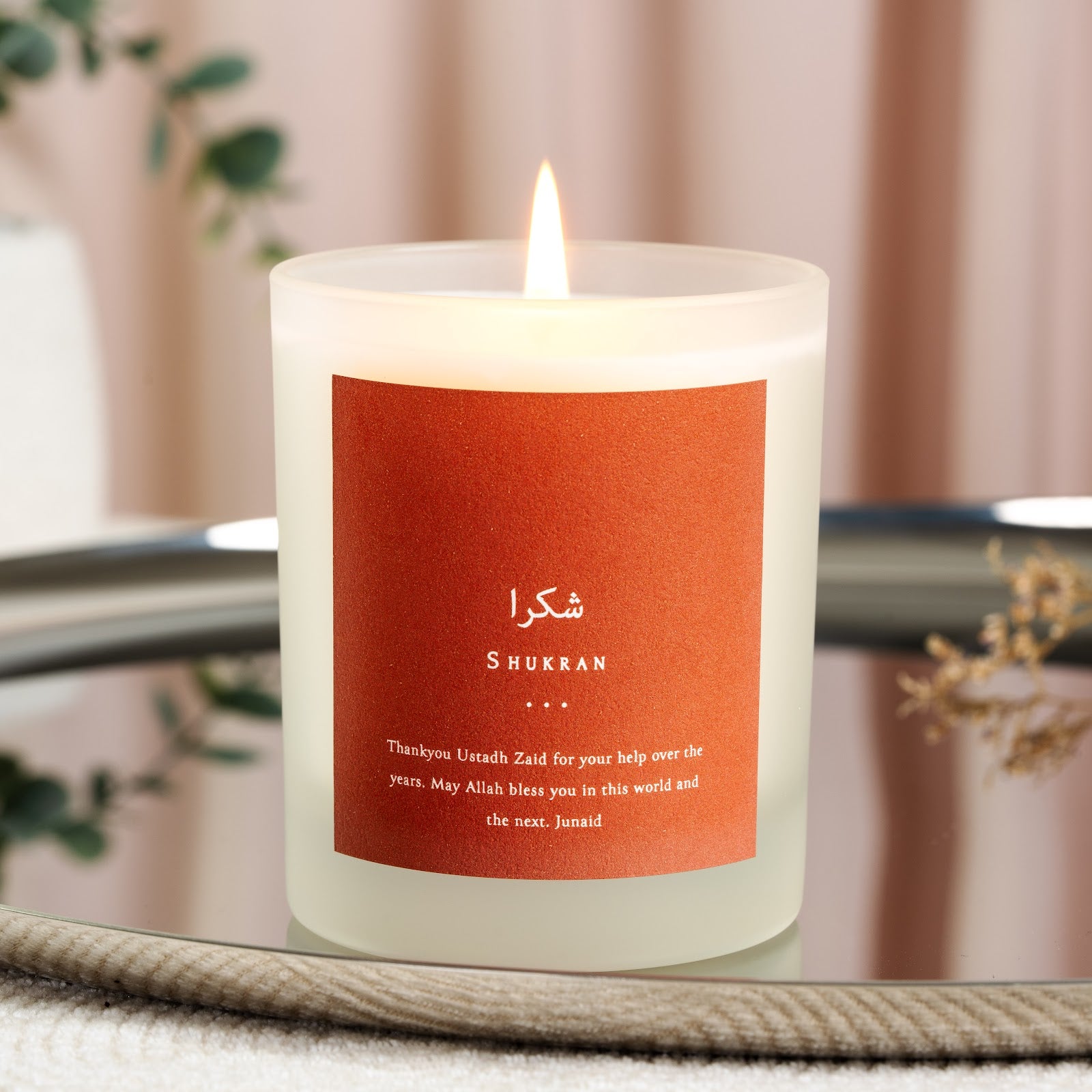 Rust background holding Shukran in Arabic above white capitals on a personalised candle