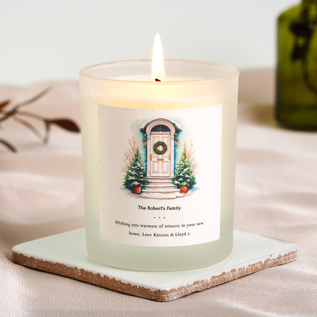 Illustrated front door framed by frosted evergreens on a personalised new home candle