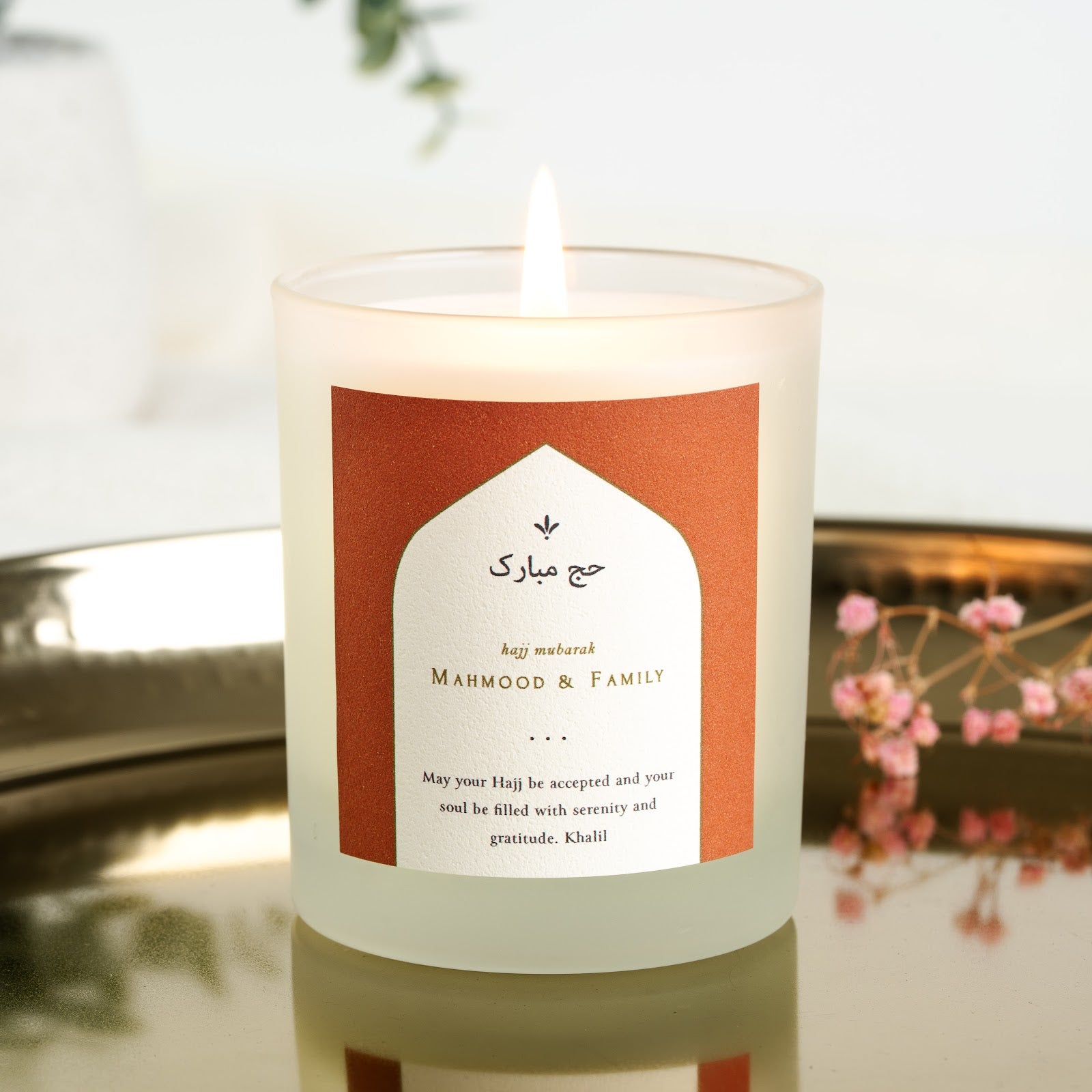 Arch-shaped label on a terracotta background on a personalised Hajj candle