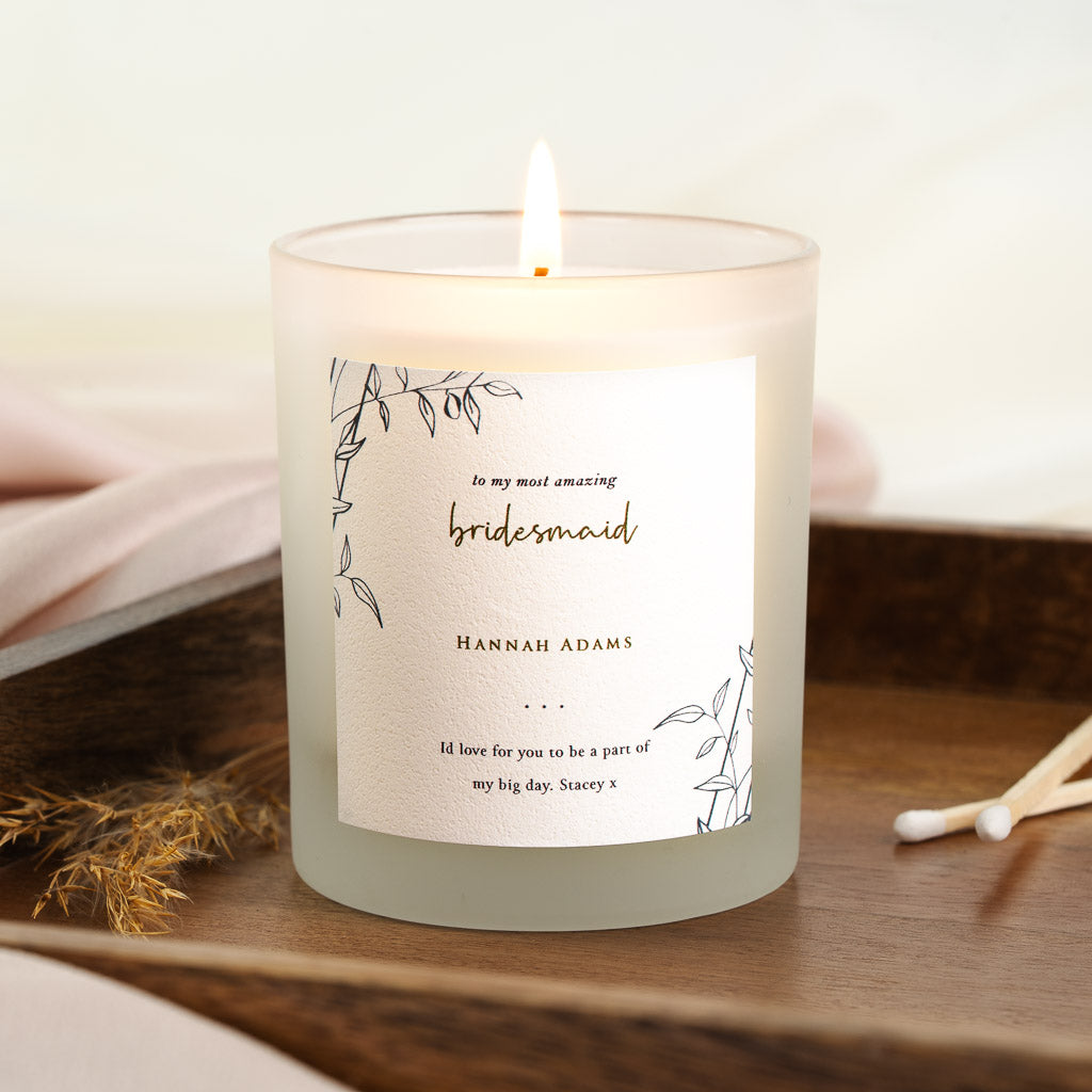 Line-drawn leaf sprigs in opposite corners of a personalised bridesmaid candle label