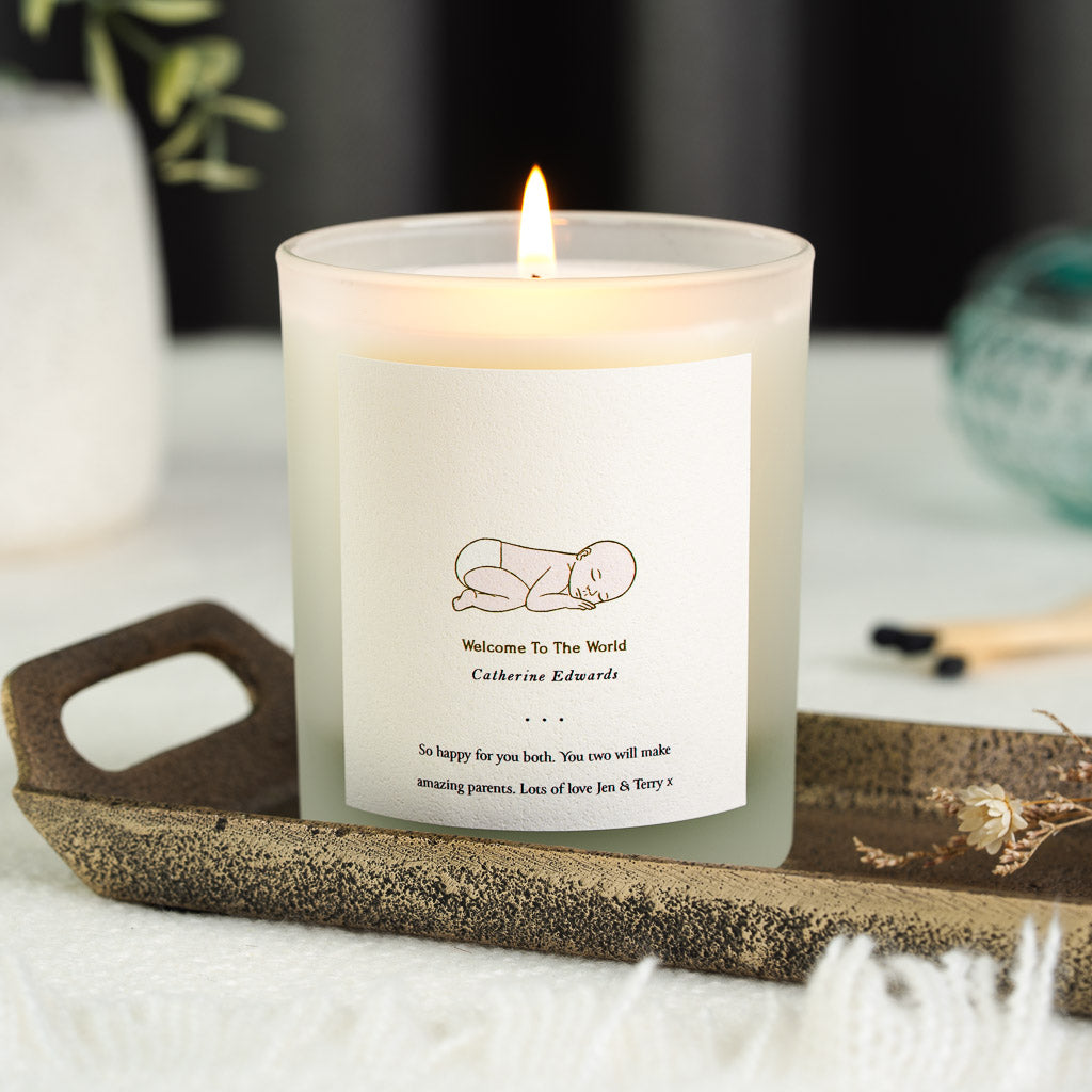 Fine gold line drawing of a sleeping newborn on a personalised new baby candle label