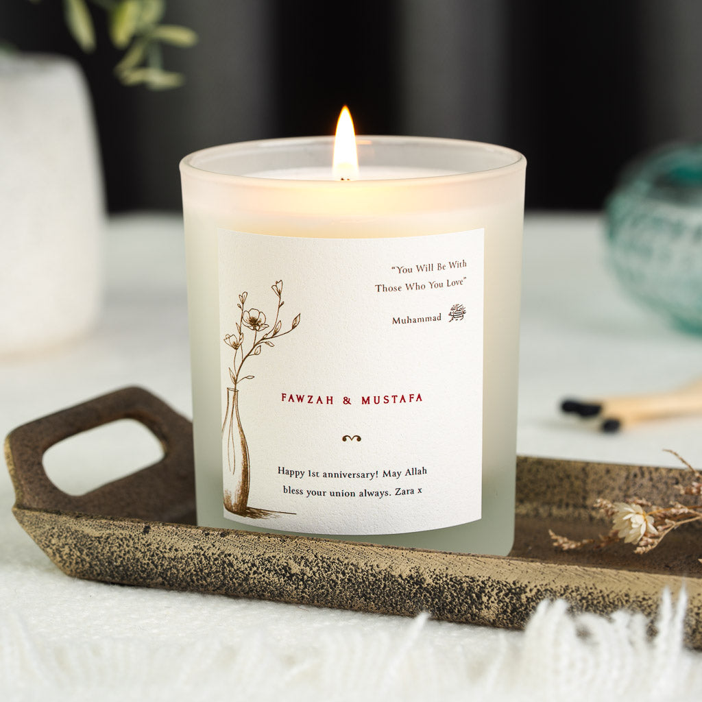 Personalised anniversary candle with a flowering branch in a vase beside a saying