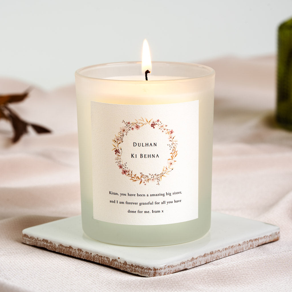 Wreath of pink and rust wildflowers framing Dulhan Ki Behna on a personalised bridesmaid candle