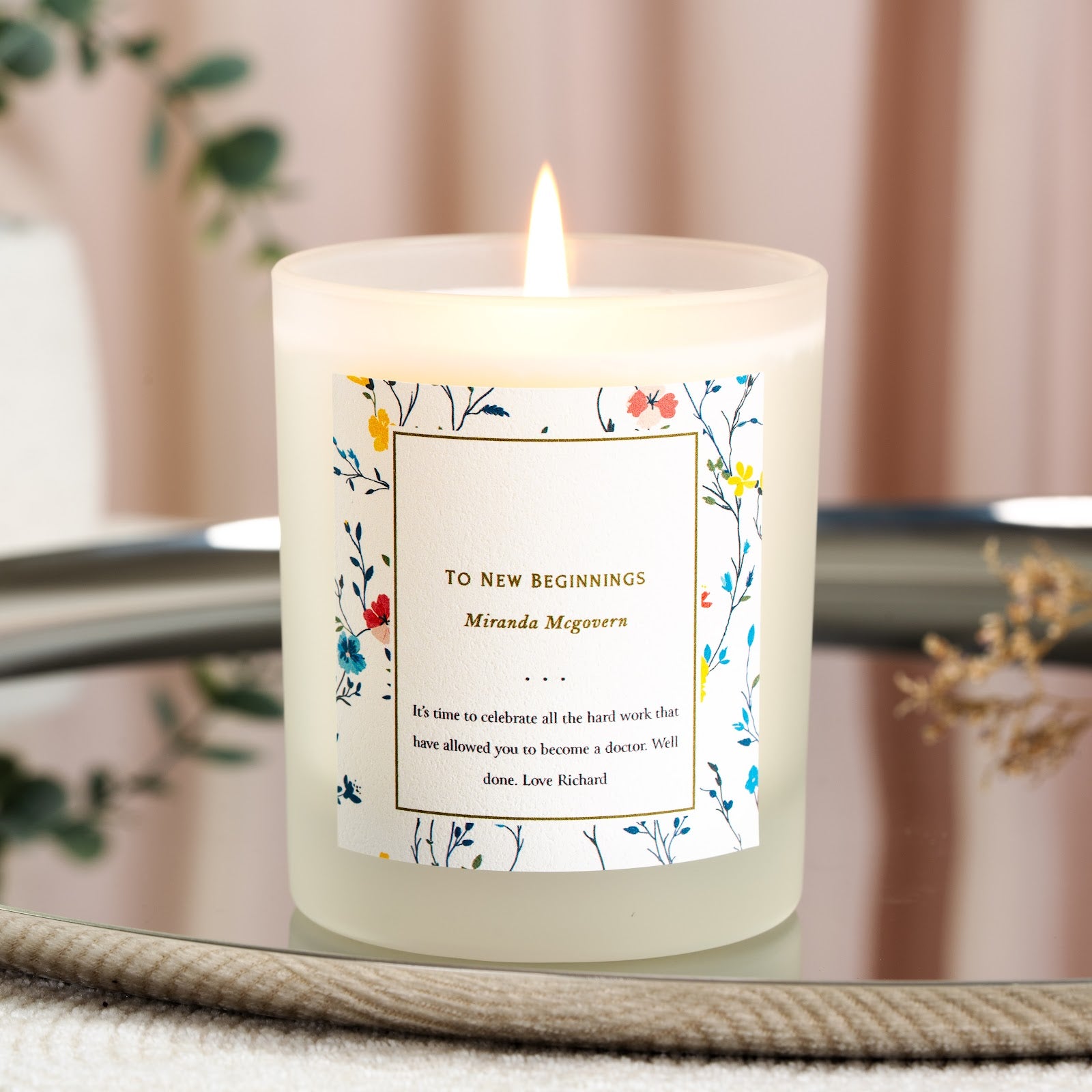 Personalised congratulations candle with a dense floral border framing a gold-toned panel