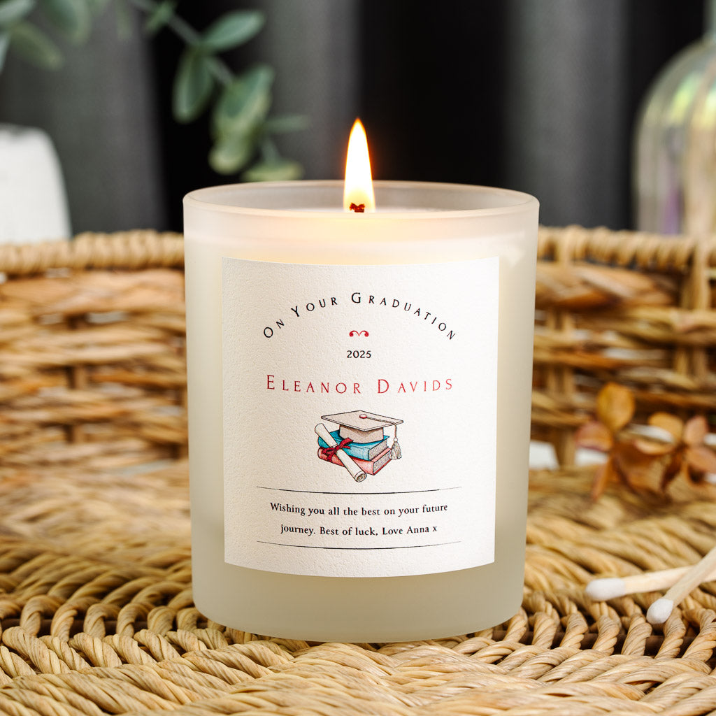 Book stack, cap and rolled scroll beneath a curved heading on a personalised graduation candle