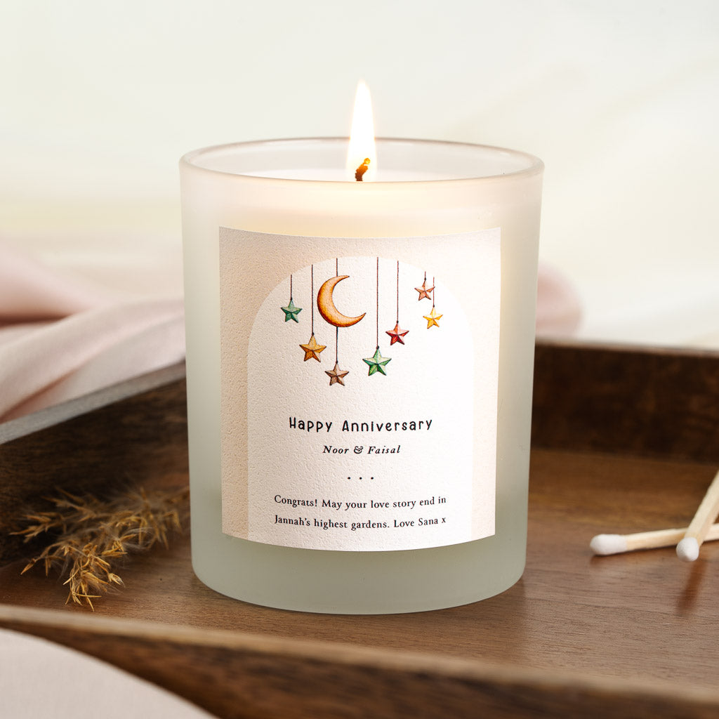 Personalised anniversary candle with coloured stars and a gold crescent on a blush arch