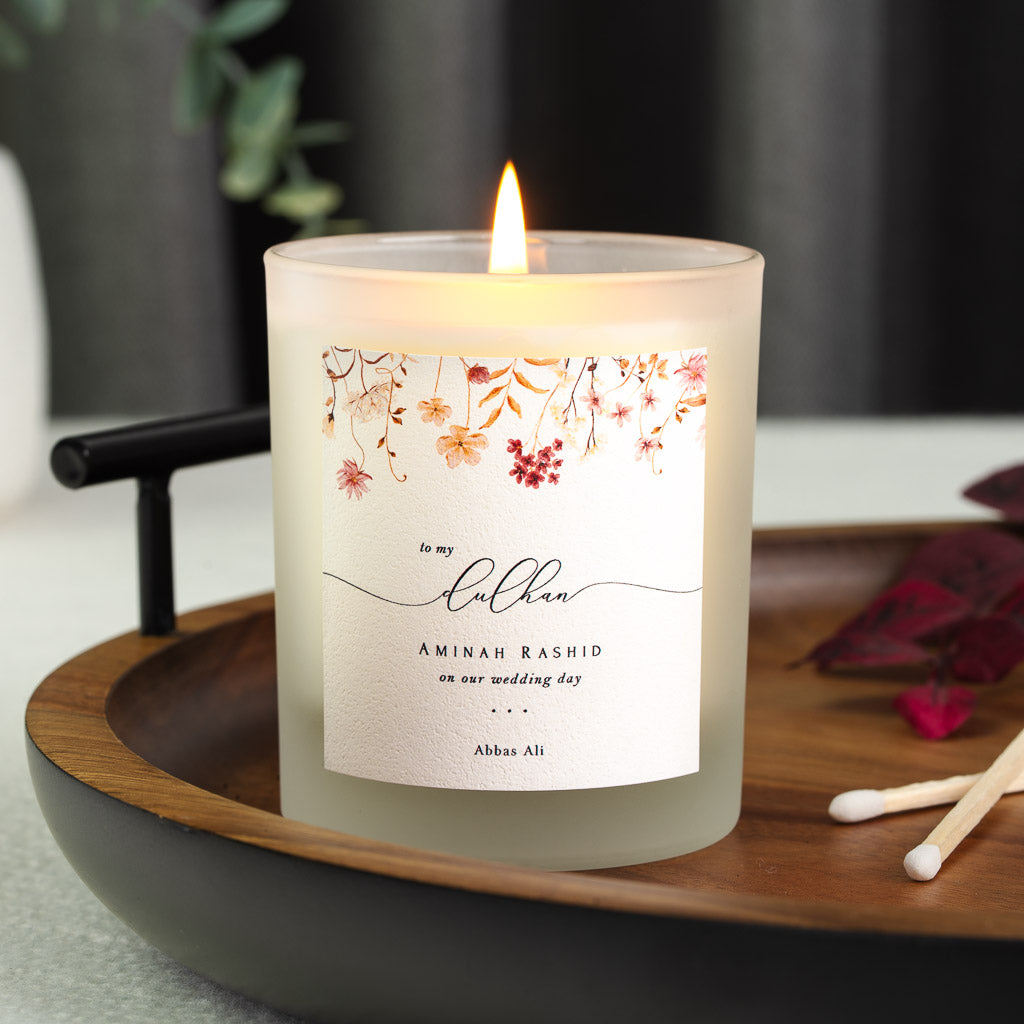 Personalised wedding candle with warm-toned pressed florals above dulhan in flowing script