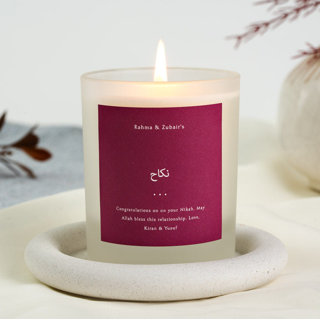 Personalised nikah candle with the names in white type on a deep berry label