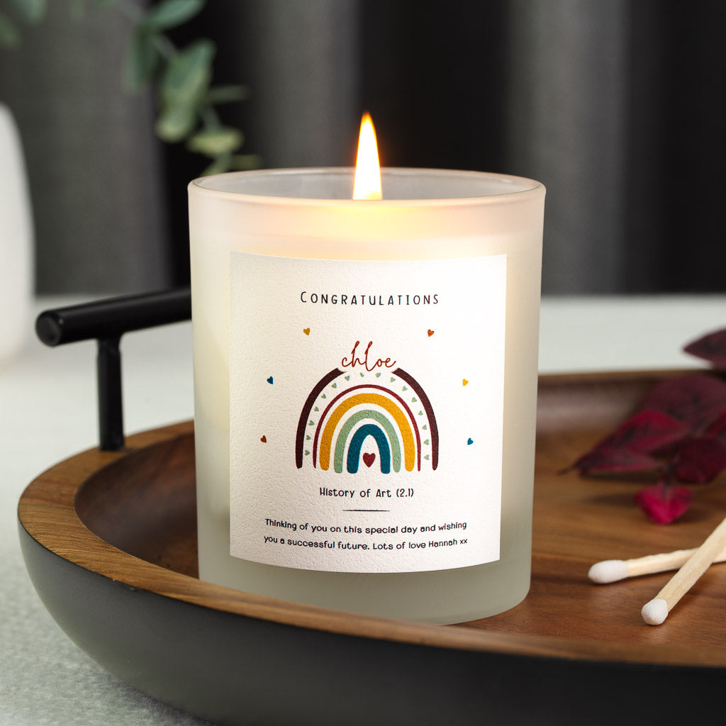 Personalised graduation candle with a deep red and gold rainbow arching over a small heart