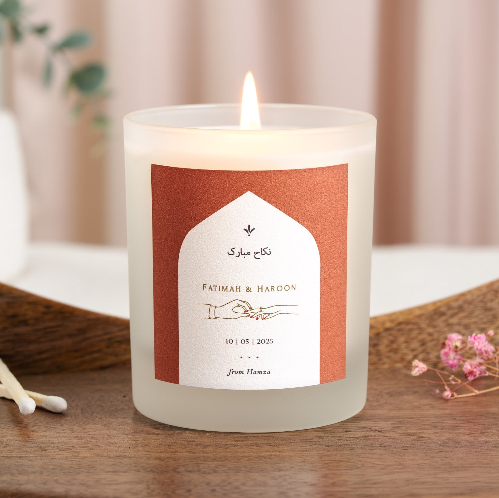 Small leaf motif above the names in Arabic on a terracotta personalised nikah candle